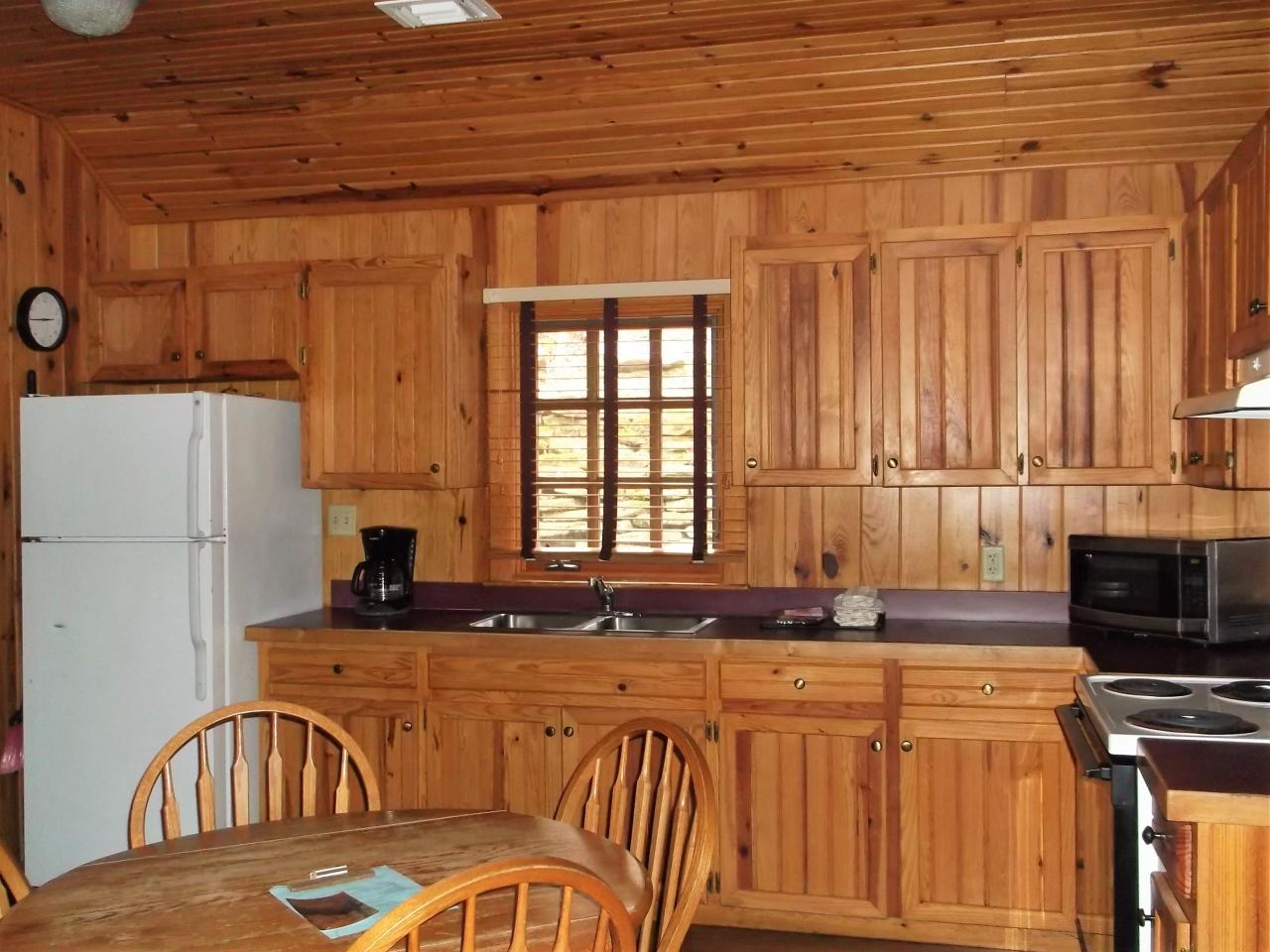 A view of the kitchen in cabin 10 including a fridge, oven, microwave, double sink and dining area